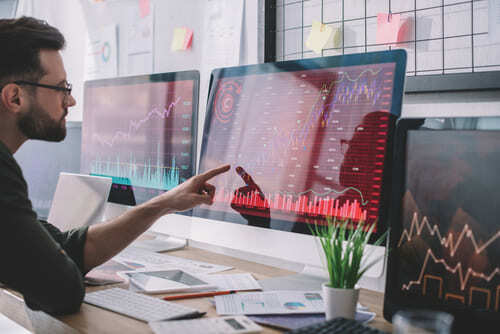 a network security analyst points to a red computer screen with charts