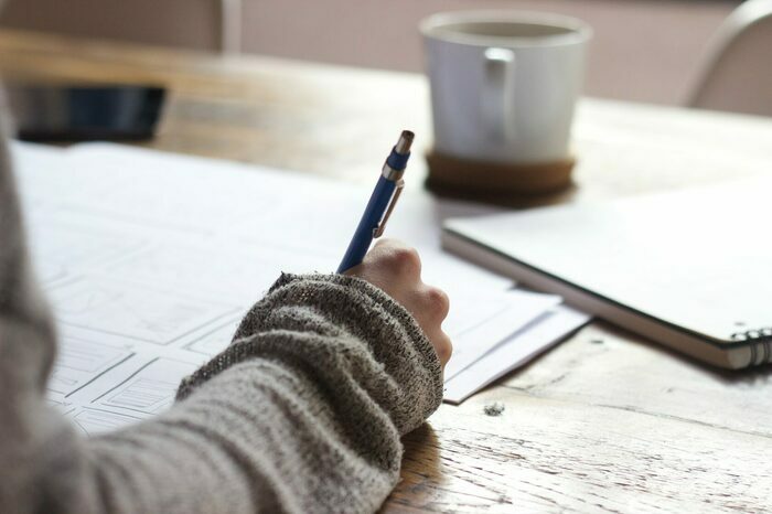 Person writing answers on a paper test, representing an achievement test