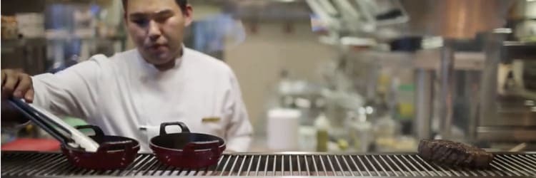 Chef cooking a steak over a grille